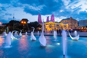 A swans fountain in the Baki Bulvari with Flame Towers in the background at twilight A swans fountain in the Baki Bulvari with Flame Towers in the background at twilight
