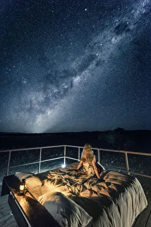 Tourist sitting on a bed outdoor admiring the stars of the Southern Hemisphere, Namibia, Africa Tourist sitting on a bed outdoor admiring the stars of the Southern Hemisphere, Namibia, Africa
