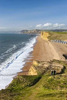 Two walkers enjoy the view along the beautiful vista from the cliffs of Burton Bradstock Two walkers enjoy the view along the beautiful vista from the cliffs of Burton Bradstock