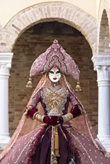 A woman wearing an Indian style costume and mask poses in the cloisters of Chiesa di San A woman wearing an Indian style costume and mask poses in the cloisters of Chiesa di San