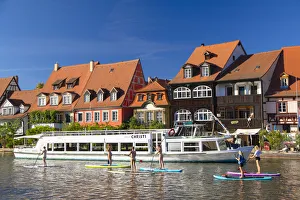 Women paddleboarding past houses of Klein Venedig (Little Venice), Bamberg (UNESCO Women paddleboarding past houses of Klein Venedig (Little Venice), Bamberg (UNESCO