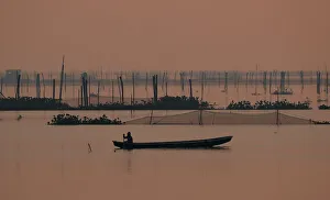 A fisherman rows his canoe as he inspects a fish cage at Laguna de Bay in Muntinlupa A fisherman rows his canoe as he inspects a fish cage at Laguna de Bay in Muntinlupa