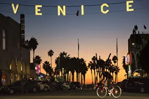 A man rides a bicycle under the Venice sign on Windward Avenue in Venice, California A man rides a bicycle under the Venice sign on Windward Avenue in Venice, California