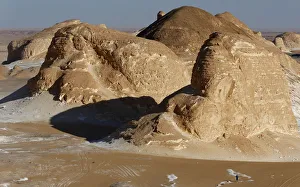 A man walks near rocks which are known as 'Ajabaat Rocks' in the White Desert near A man walks near rocks which are known as 'Ajabaat Rocks' in the White Desert near