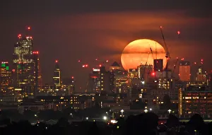 The full moon is seen rising behind skyscrapers at Canary Wharf and the London skyline The full moon is seen rising behind skyscrapers at Canary Wharf and the London skyline