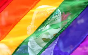 A participant stands behind a rainbow flag during a gay pride parade promoting lesbian A participant stands behind a rainbow flag during a gay pride parade promoting lesbian