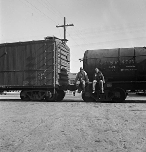 RAILROAD, 1937. Itinerant men riding outside a train hauling oil tanks in Kingsbury RAILROAD, 1937. Itinerant men riding outside a train hauling oil tanks in Kingsbury