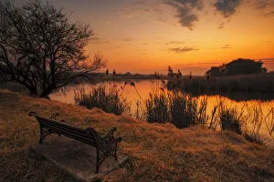 Lonesome park bench at sunset on the shores of a remote farm lake near Magaliesburg Lonesome park bench at sunset on the shores of a remote farm lake near Magaliesburg