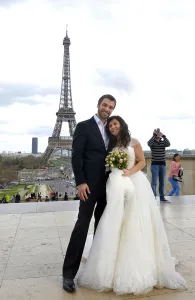 A mixed American and Roumanian newly married couple poses in front of the Eiffel tower A mixed American and Roumanian newly married couple poses in front of the Eiffel tower