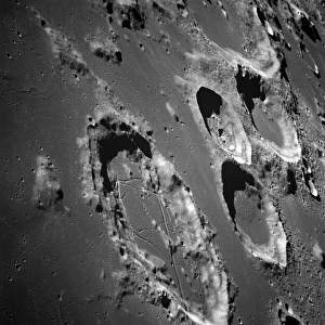 <b class=qtipBold><figcaption>Oblique view of the lunar surface</figcaption></b><br>December 1968 - This oblique view of the lunar surface was taken from the Apollo 8 spacecraft looking southward toward Goclenius and other large craters in the Sea of Fertility. Goclenius, the crater in the foreground with a rille-broken flat floor, is about 70 kilometers (45 statute miles) in diameter. One rille, approximately horizontal in this view, crosses both crater rims and the central peak, and, on adjoining Apollo 8 photographs, can be traced several kilometers across the mare surface beyond the high crater wall. In the background, the two large craters with smooth floors are Colombo A (left) and Magelhaens. Magelhaens A, the crater with the irregular floor, is about 35 kilometers (20 statute miles) in diameter.<br><em>© Stocktrek Images</em> Oblique view of the lunar surface
